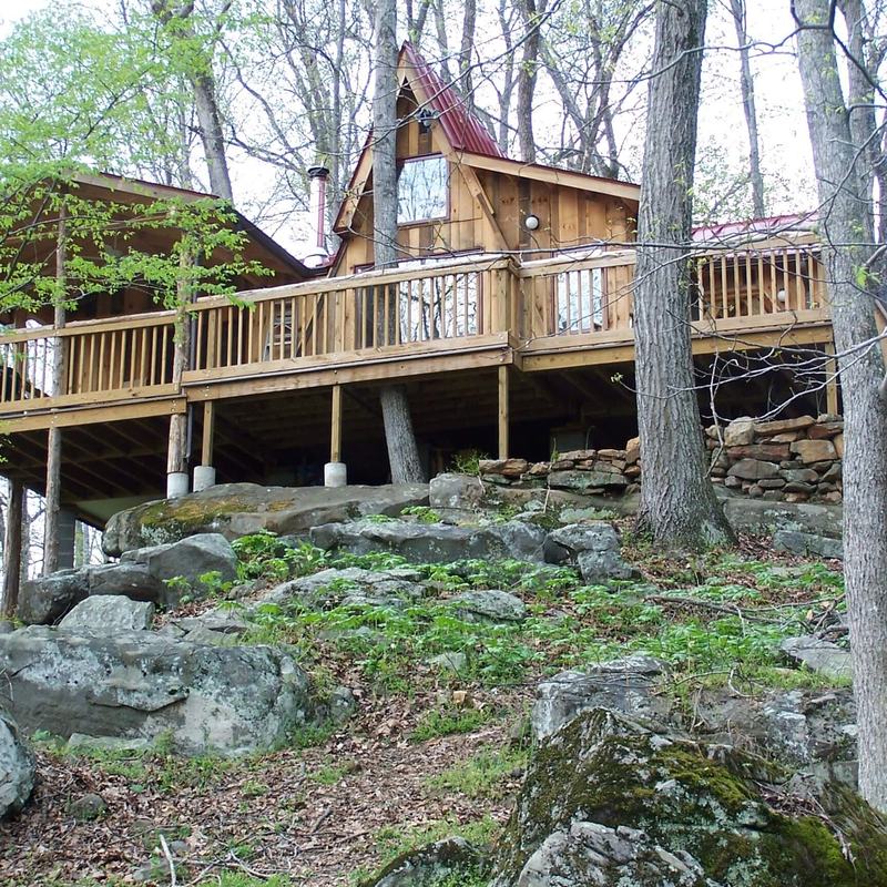 Cabin with a wraparound deck set in the woods