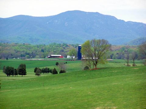 Blue Ridge Mountains above green pastures and a farm with a blue silo