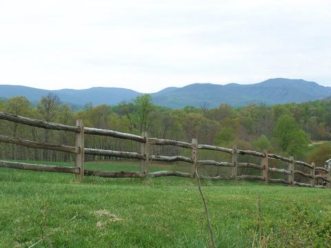 Split rail fence along a pasture with mountains on the horizon