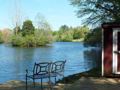 Bench beside a pond with a red boathouse