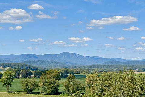 Blue Ridge Mountains under a blue sky with puffy white clouds and green fields below