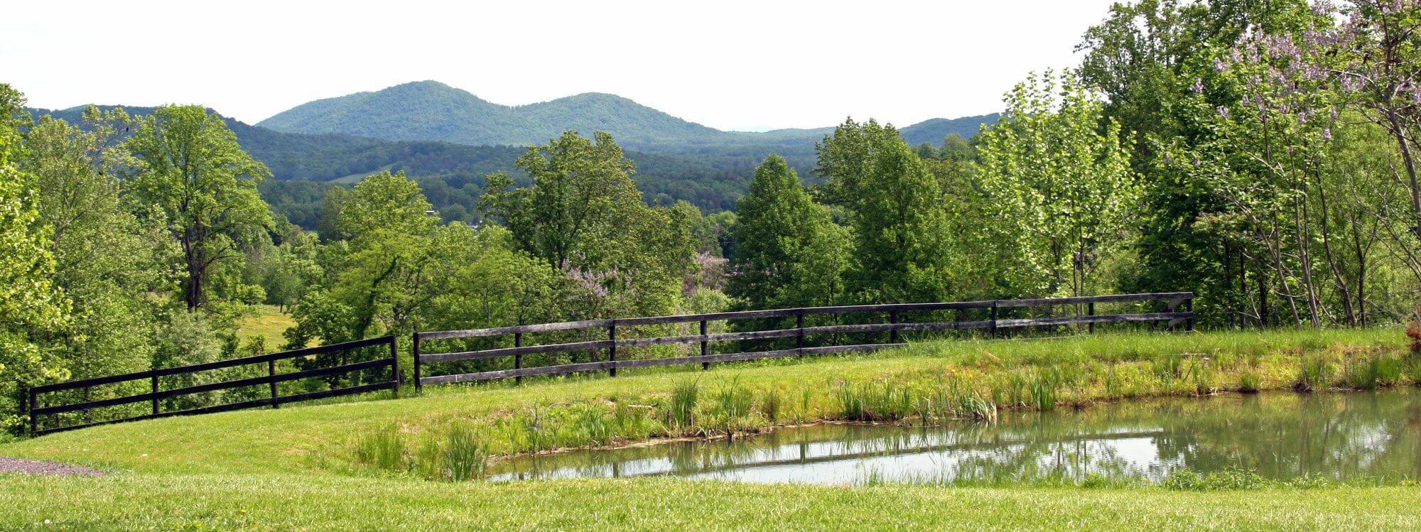 Pond and black board fence below the mountains